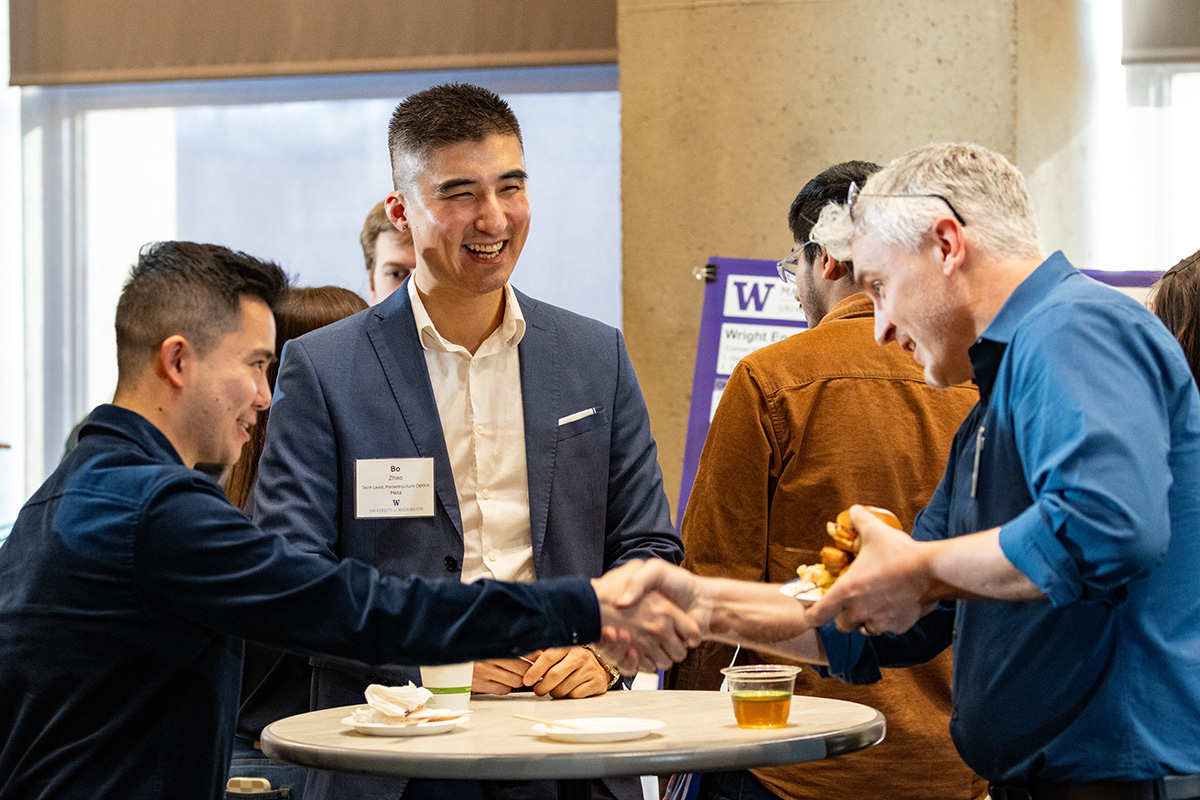 Three men smiling and shaking hands.