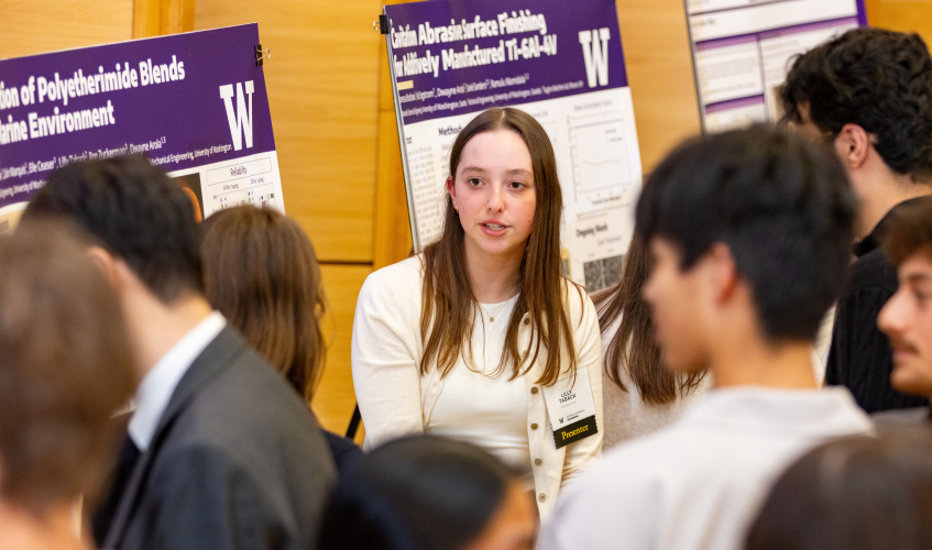 MSE students discuss research in front of poster boards. 