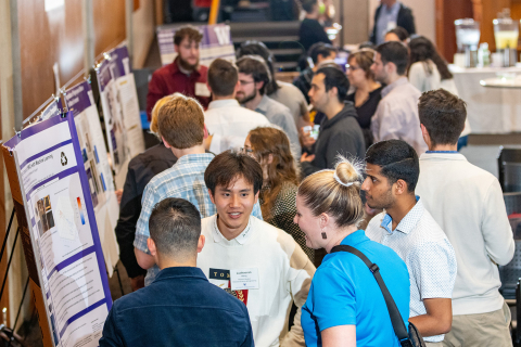 A crowd of people in a reception hall viewing academic research posters
