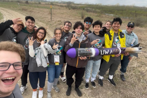 A group of twelve people holding a rocket