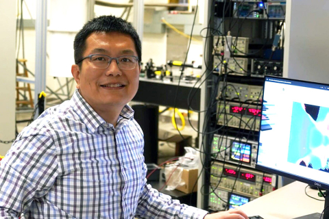 Xiaodong Xu sits at a computer in his lab