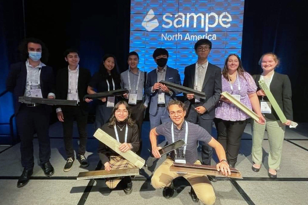 Ten UW SAMPE team members holding their winning bridge design at the 2022 competition