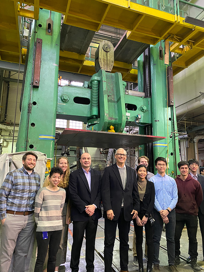 Inslee, Arola and team in front of CEE lab equipment that can test zeolite concrete under as much as 2.4 million pounds of force.