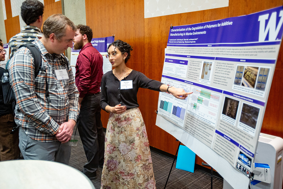 MSE senior Anushka Sarode points at her research poster, explaining the project to an event guest.