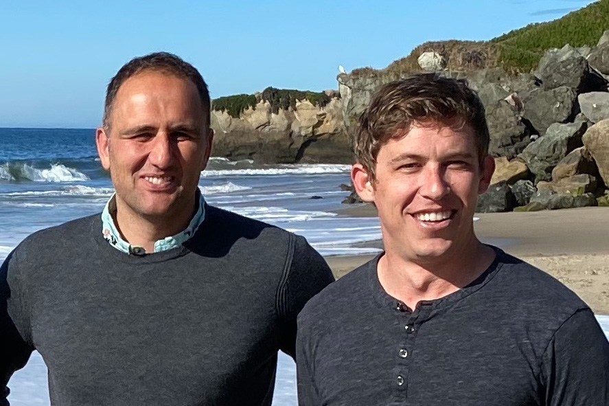 Marco Rolandi and John Felts on a beach and smiling at the camera.