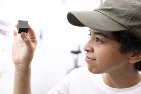 MSE doctoral student Mallory Parker holds up a sample of a new material: a bioplastic cube made from spirulina