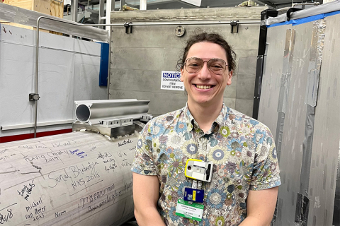 Anthony Gironda standing in front of a piece of equipment during a tour of the Oak Ridge National Laboratory