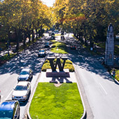 W sculpture surrounded by cars driving through campus
